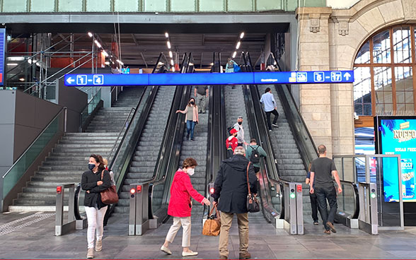 Voyageurs masqués dans la gare CFF de Bâle à moitié vide.